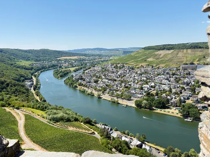 Blick über die Mosel auf Weinberge und einen Uferweg bei Traben-Trarbach